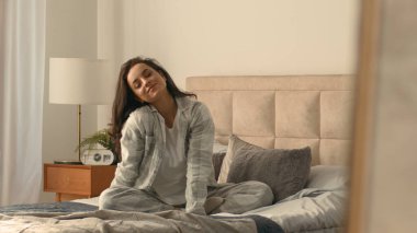Kafkasyalı Avrupalı kadın yatağında uzanıyor. Günaydın neşe dolu yatak odasını pijamalarıyla donatıyor. Rahat rahat rahatlıyor, tasasız bir hafta sonu.