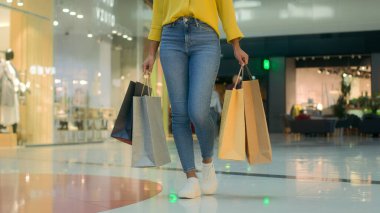 Önden bakan kadın çantalarla alışveriş merkezine gidiyor tanınmayan bir alışveriş mağazası satın alıyor modaya uygun marka moda kıyafetler alıyor yeni cuma koleksiyonu para harcıyor.