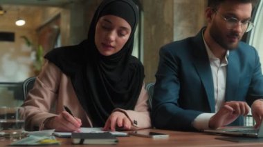 İki iş arkadaşı iş kadını, Arap Müslüman kadın firmasında birlikte çalışıyor. Hintli erkeğin bilgisayarla farklı kadın ofislerinde aynı anda bilgisayar yazdığını yazıyor.