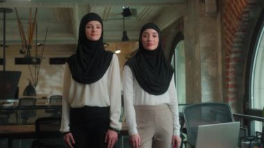 İki Müslüman kadın tesettüre girmiş güçlü iş kadınları Arap iş kadınları iş arkadaşları iş ortakları iş yerinde el ele tutuşmuş kadın iş arkadaşları.