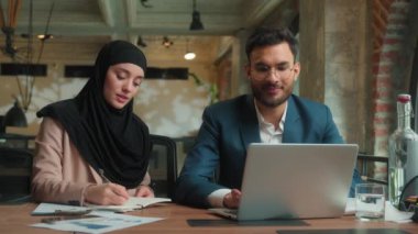 İşadamı kadın, erkek, dizüstü bilgisayarda çalışıyor. Ofiste notlar yazıyor. İki iş arkadaşı, tesettürlü Müslüman kadın.