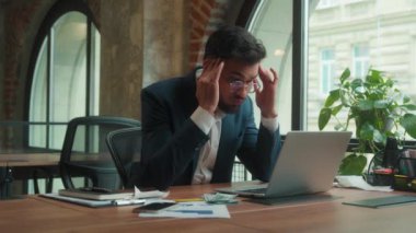 Arap Hintli iş adamı ofiste dizüstü bilgisayar başında çalışırken baş ağrısı çekiyor yorgun adam migren ağrısı çekiyor başağrısı çeken tesettürlü iş kadını cam su tıbbi sağlığını içmeye yardım ediyor
