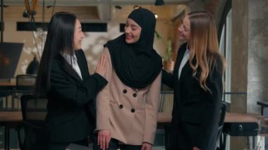 Mutlu, çok ırklı iş arkadaşları, kadın, çok ırklı iş arkadaşları, iş kadınları gülüyor, ofis portresi gülüyor, arkadaşlık birliğine sarılıyor Arap, Müslüman, Asyalı, beyaz kadınlar.