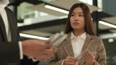 Asyalı kadın Koreli iş kadını stajyer kız para sayıyor üzgün üzgün zengin zengin iş adamı erkek lider iş adamı iş adamı eşitsizliğine bakıyor
