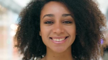 Afro-Amerikalı genç mutlu kadın kameraman dişlek dişçi kız gülüşüne bakıyor eğlenceli zevkler bayan öğrenci alışveriş merkezi pozitif alışveriş merkezi alıcısı yüz ifadesi