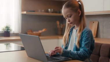 Gadget bağımlısı küçük kız bilgisayar oyunu yazarken modern teknoloji kullanarak sosyal medyada sohbet ederek ev mutfak dizüstü bilgisayar bağımlılığı nesli internet teknolojisi e-öğrenerek uzaktan eğitim alıyor.