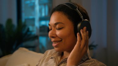 Afro-Amerikalı kadın gülümseyen iş kadını bilgisayar işinde çalışıyor kadın serbest çalışan kablosuz kulaklıklarda sesin keyfini çıkarıyor bilgisayardaki müzik uygulamasını dinliyor uzaktan iş karantinasında dinleniyor