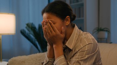 Sorrowful upset African American woman stressed girl suffer headache grief sorrow depression crying lady at night evening home close face with hands worried mental problem breakup unwanted pregnancy