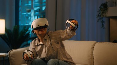 VR başlıklı Afro-Amerikan kadın sanal gerçeklik oyunu oynuyor. Şaşırmış kız oyun kumandaları kullanıyor. Oyun simülasyonları yapıyor.