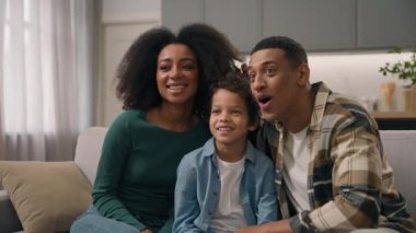 Heyecanlı, neşeli, Afro-Amerikan, etnik aile babası, küçük çocuğu kucaklayan, oyun oynayan, ebeveynlik yapan çocuk TV 'de komik bir film seyreden, suratını asan, evde otururken suratını buruşturan çocuk.