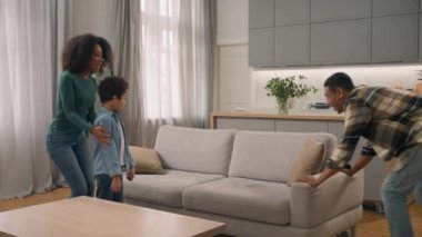 Heyecanlı, mutlu, Afro-Amerikan, etnik, aile kadını, küçük çocuk güçlü adam yeni kanepe mobilyaları getiriyor, sonra anne baba oğul evde dinlenip dinleniyor.