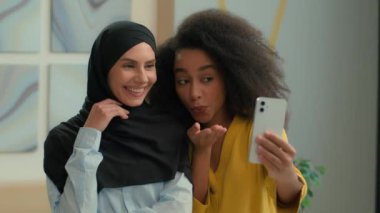 Çok ırklı iş kadınları tesettürlü mutlu Afro-Amerikan müslümanlar, tesettürlü iş kadınları, blog yazarları, modeller, ofisteki cep telefonlarının sosyal medya fotoğraflarını çekiyorlar.