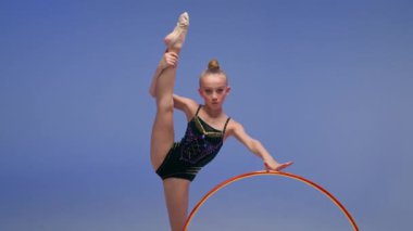 Kafkasyalı küçük kız çocuğu kız çocuk jimnastikçi kız, dansçı, dansçı, dansçı, akrobat bölünmüş pozisyonda esnek sanatsal jimnastik, dönen çember sporu stüdyosu mavi arka plan