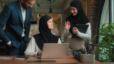 Arap erkek işadamı kadın işkadını, laptopta çalışan bir çalışana geldi. İki akıl hocası, öğrencilere danışmanlık desteği verdi.