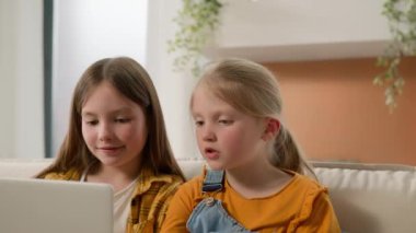 İki mutlu Kafkasyalı kız çocuk çocukları çizgi film izleyen kız kardeşler dizüstü bilgisayar kullanıyorlar çizgi film arkadaşlarıyla sohbet ediyorlar oyun kanepede oyun oynuyorlar. İnternet bağımlılığı