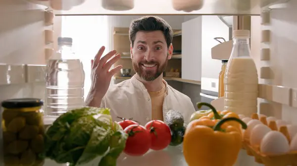 stock image Point of view from inside refrigerator POV Caucasian man householder homeowner open fridge door kitchen full of products food smiling find take red tomato happy smile cooking salad healthy vegetarian