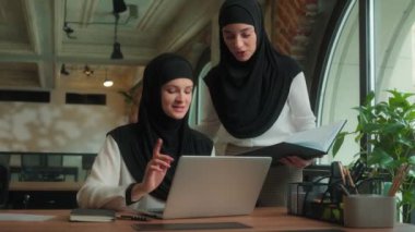 İki Müslüman İslami iş kadını meslektaşı kız iş kadını ofis şirketinde birlikte çalışan tesettürlü iş kadını kadın lider çalışana danışmanlık öğretmesi için yardımcı oluyor.