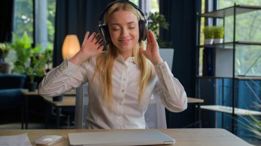 Kafkasyalı iş kadını ofis masasında gerinerek bilgisayar işini bitirdi mutlu, rahat iş kadını kadın, stres, işten sonra rahatlama, gülümseme, tatmin olmuş kız kulaklık tak, müzik dinle.