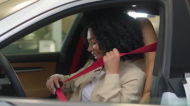 Afro-Amerikalı kadın mutlu müşteri alıcısı bayan sürücü galeride lüks bir arabanın içinde oturmaktan zevk alıyor emniyet kemeri takmaktan emniyet kemeri takmaktan otomobil test sürüşü yapmaktan araba satın almaktan yeni bir araç seçmekten