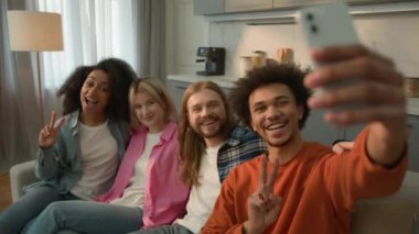 Çok ırklı insanlardan oluşan bir grup Kafkasyalı kız Afrikalı Amerikalı kadın erkekler kanepede poz veren erkekler cep telefonu etkili blogcusu ile selfie çekiyorlar.
