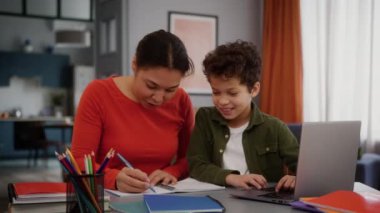 Afro-Amerikan ailesi mutlu bir şekilde gülümsüyor anne kadın ev ödevlerine online olarak yardım ediyor e-kitap yazmayı öğreniyor çocuk çocuk okul çocuğu oğlunu kandırarak eğlendiriyor.