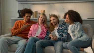 Çok ırklı insanlar, çok ırklı arkadaşlar, öğrenciler, Kafkas kadın kızlar, Afrikalı Amerikalı erkekler, erkek kanepe, cep telefonlarına bakarak sosyal medya haberlerini tartışırlar.