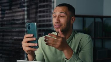 Gülümseyen Afro-Amerikalı adam görüntülü konuşma yapıyor. Erkek iş adamı serbest girişimci. İnternet konferansını telefonla arıyor.