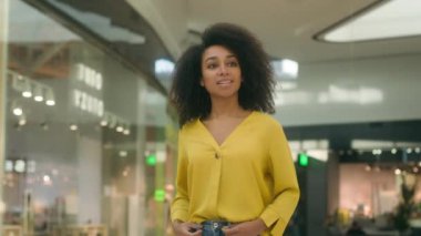 Afro-Amerikan kadın alışveriş merkezinde yürüyen butik Kara Cuma alışverişi müşterisi yeni koleksiyon kızı satın alıyor vitrin mankeni mağazası satış indirimine bakıyor.
