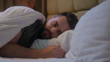 Kafkasyalı bir adam yatak odasında uzanıyor uykusuzluk sorunu düşünceli, kaygılı, yatma vakti ev kredisi, melankolik, kederli, kederli, yorgun.