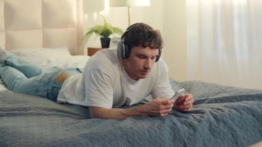 Mutlu adam kulaklıkları cep telefonu akıllı telefon dans eden erkek müzik söyleyen yatak odası elektronik cihaz teknolojisi şarkısı hafta sonu eğlencesinin tadını çıkar ses melodisi dinlendirici