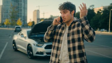 Stresli Kafkasyalı adam şehir arızalı arabasında cep telefonu konuşuyor. Kaput kapağı açık araba kazası. Araba kazası.