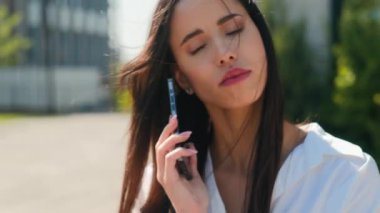 Yakından bakınca kafası karışmış, düşünceli İspanyol bir kadın açık havada cep telefonuna cevap veriyor. Düşünceli, şaşkın, iş kadını bir bayan iş kadını.