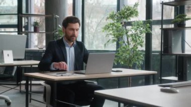 Odaklanmış Kafkasyalı iş adamı satış temsilcisi erkek yönetici ofiste çalışan dizüstü bilgisayarla yazı yazan internet planlama projesi stratejisi hakkında notlar yazan şirket çalışanı