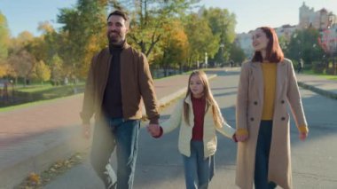 Sokak sohbetinde yürüyen mutlu Kafkas ailesi anne, baba, kız, liseli kız el ele yürüyüp sonbahar gezintisinde tatilden bahsediyorlar.