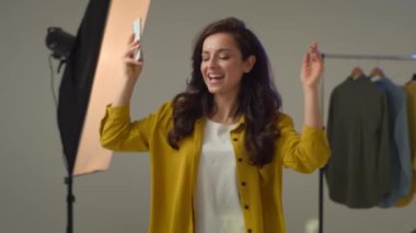 Kaygısız, beyaz kadın, blog yazarı, gülümseyen, dans eden cep telefonu hoparlörlerini açan, neşeli kadın blogcu. Model vlogger flaması. Stüdyoda tek başına taşınan şarkının tadını çıkarıyor.