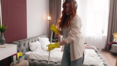 Beyaz kadın yatak odasında tek başına temizlik yapıyor. Ev işlerini yapıyor. Ev işlerini yapıyor, yerleri paspaslıyor.