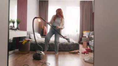 Kafkasyalı komik kadın bayan ev hanımı ev işleri mutlu ev sahibi elektrikli süpürge ile evde tek başına dans ediyor gitar çalıyor gibi yapıyor eğlence dansı yapıyor gibi yapıyor.