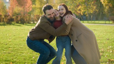 Beyaz, mutlu, aile babası, anne, kız çocuğu, gülümseyen, gülen, kucaklaşan, güneşli sonbahar parkında kucaklaşan çocuk bakımı yapan anne ve baba.