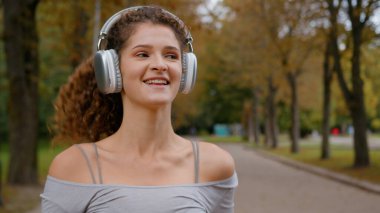 Gülümseyen, kaygısız, pozitif, mutlu, beyaz kadın koşucu. Parkta koşan kulaklıkla şarkı dinle. Gülümse, spor yap, spor yap, spor yap.