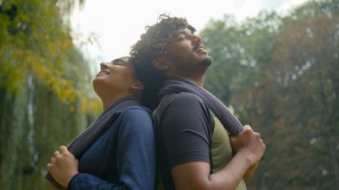 Yorgun, terli iki sporcu dinleniyor sırt sırta uzanıp konuşuyor erkek Hintli, kadın, Arap, erkek, kadın havluyla spor yaptıktan sonra rahatlıyor.