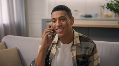 Gülümseyen Afrikalı, etnik erkek, gülümseyen, kaygısız, erkek, konuşan, akıllı telefon konuşan, cep telefonuyla konuşan, gülen, sohbet eden, kanepe kanepesinde sohbet eden, mutlu sohbet eden.