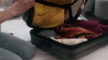 Tanımlanamayan bir kadın seyahate çıkmaya hazırlanıyor. Turizm turizmi hazırlığı. Evde tatil için giysi valiziyle birlikte valize yılanı yapıştırın.