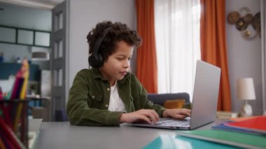 Afrika kökenli küçük çocuk oyuncu çocuk erkek kullanıcı internet oyunu dizüstü bilgisayar oyunu oynuyor evde kablosuz kulaklıkla oynuyor zafer kutlamaları başarıyla sonuçlandı