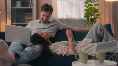 Çok ırklı çift zımbırtısı aile internet bağımlılığı sosyal medya bağımlısı beyaz erkek, dizüstü bilgisayar kadın, cep telefonu sohbeti, kahkaha gülüşü.