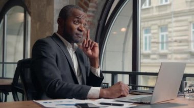 Afrikalı Amerikalı orta yaşlı girişimci, bilgisayar bilgisayarı kullanarak düşünceli bir çözüm üretiyor. Düşünceli bir karar vermeye çekiniyor. Fikir adamı ofis işadamı, iş adamı, dizüstü bilgisayarı yazan adam.