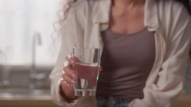 İspanyol beyaz kadın kız mutlu bir bardak hala maden suyu içiyor mutfakta organik içecek gülümseyen diyet, su dengesi, beslenme, göz kırpması gülümsemesi