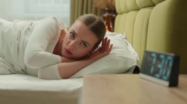 Yorgun ve uykulu bir kız sabah yatağında uyanıyor uykusuzluk sorunu, uykusuzluk sorunu, uykusuzluk, uykusuzluk sorunu, kadın alarm saatinden yüksek sesle çalan kadın.