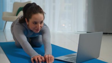 Spor giyim bölümünde vücut esnetme sporu yapan bayan antrenörü spor salonunda spor eğitmeni beyaz kadın sporcu kız paspasın üzerinde poz vermeyi öğreniyor.