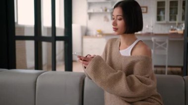 Kafkasyalı İspanyol kadın, sıradan bir kız gibi kanepede oturuyor. Kadın kullanıcı etkisinde rahatlamak için cep telefonu internet bağımlılığı akıllı telefon siparişi veriyor.