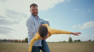 Neşeli beyaz erkek ebeveyn baba baba baba birlikte oynuyorlar fırıl fırıl dönen oğul kucağında çocuk taşırken kırsal alanda iyi eğlenceler doğa mutlu aile çocukluk oyunu